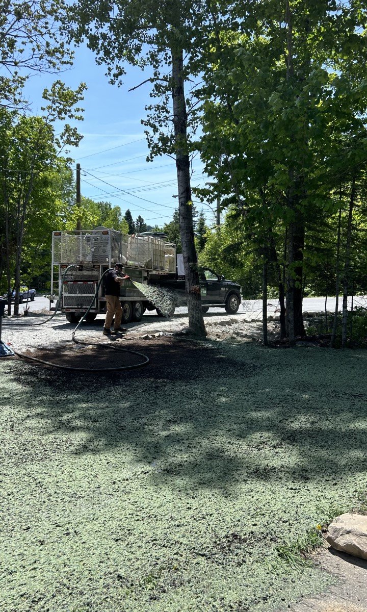 Travailleur appliquant l’hydro-ensemencement  à Rivière-Rouge avec un camion spécialisé, démontrant la projection de semences et mulch sur un terrain.